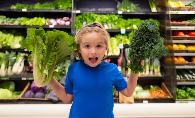 Niño con verduras en la tienda de comestibles niño eligiendo comida en la tienda de comestibles o en un supermercado fruta y v