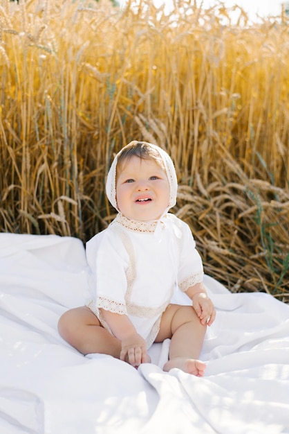 Niño vestido de blanco se relaja al aire libre en un campo