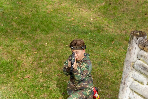 Niño vestido de camuflaje jugando a la etiqueta láser en un parque infantil especial