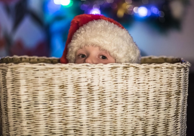 Niño vestido como Papá Noel que se sienta en una cesta grande