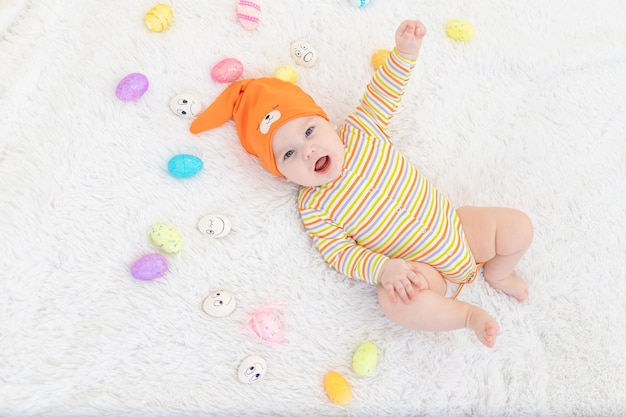 Niño vestido de naranja acostado con huevos de Pascua lindo y divertido bebé sonriente El concepto de Pascua