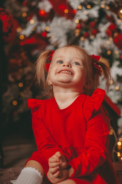 niño en vestido rojo con árbol de navidad