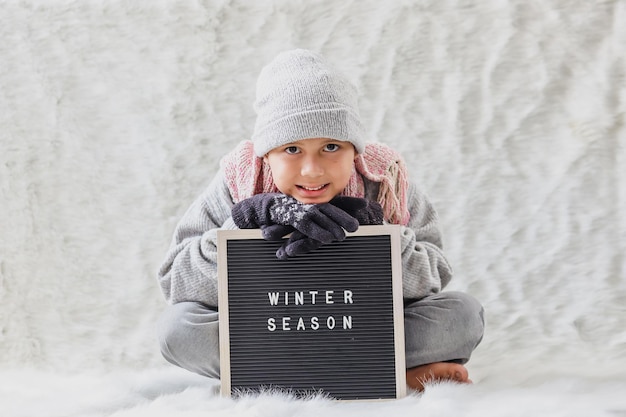Un niño vestido con ropa de invierno da la bienvenida felizmente a la temporada de invierno.