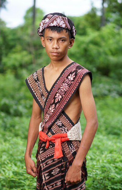 Un niño con un vestido tradicional se para en un campo.