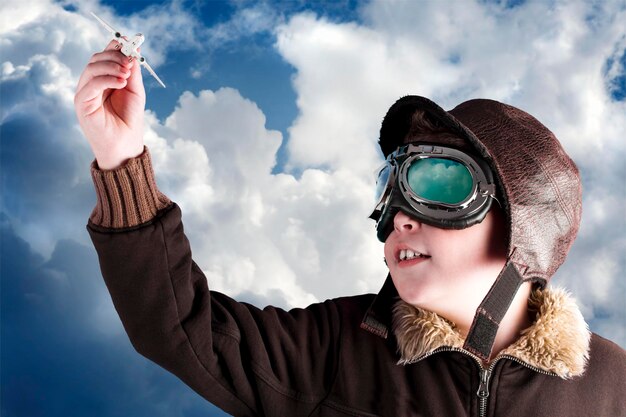 Niño vestido con traje de piloto, chaqueta, sombrero y gafas.