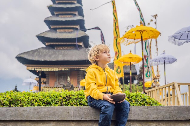 Niño viajero en el fondo del templo hindú pura ulun danu bratan bali rodeado de flores en