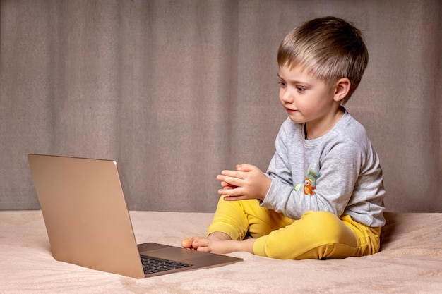 Niño viendo dibujos animados en una computadora portátil en el dormitorio en la cama