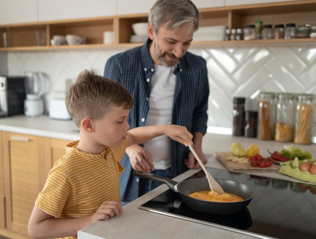 Foto niño viendo padre cocinar tortilla