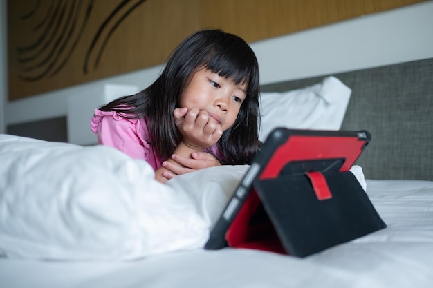 Niño viendo tableta en la cama niño adicto dibujos animados