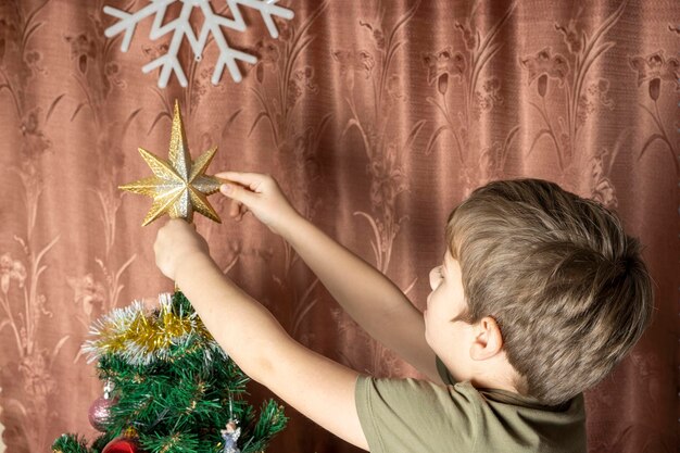 Un niño viste un árbol de Navidad con juguetes.