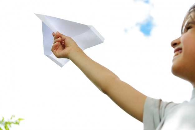 Foto niño volando un avión de papel