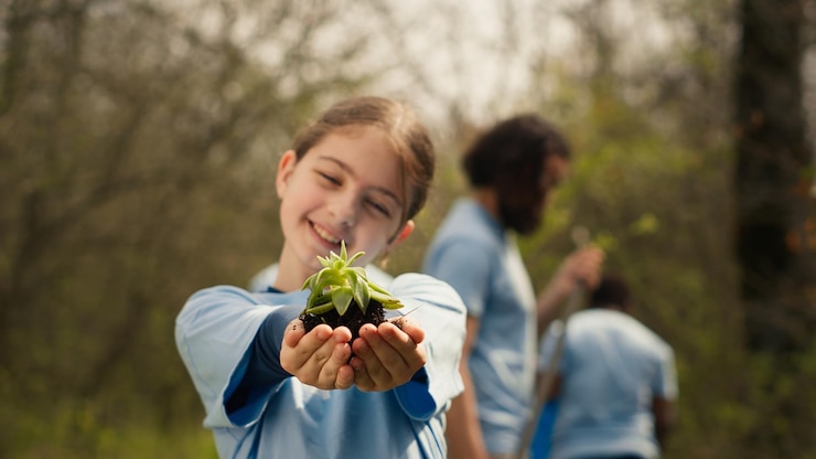 Foto niño voluntario sosteniendo una pequeña plántula con tierra natural en las manos