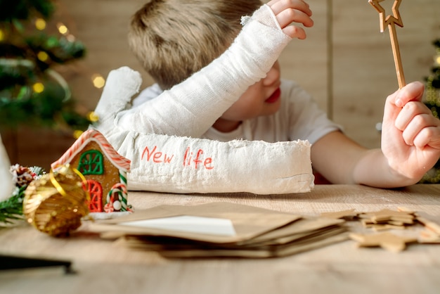 Niño con yeso en el brazo hace manualidades navideñas. Fractura y lesión de mano. Quita el yeso, esperando una nueva vida.