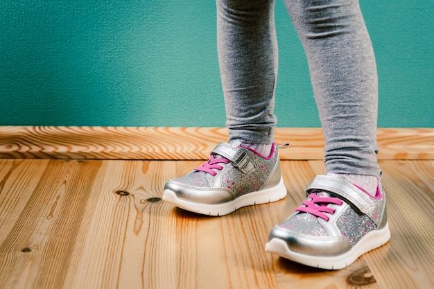 Niño en zapatillas sobre superficie de madera