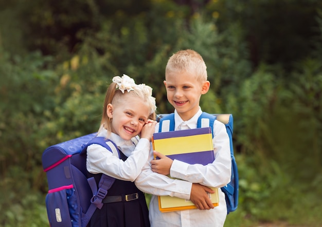 niños de 7 a 8 años, estudiantes de primaria con mochilas y uniformes escolares, sonriendo