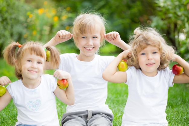 Niños activos felices con manzanas divirtiéndose en el parque de primavera Concepto de alimentación saludable