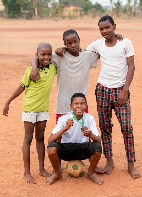 Niños africanos con pelota de fútbol y medalla.