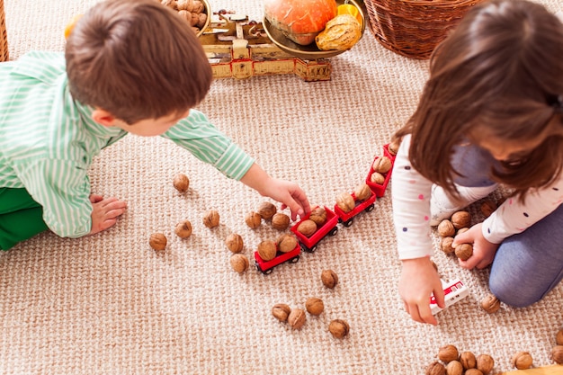 Los niños agregan nueces en un tren de juguete y aprenden a contar sentados en el suelo en el jardín de infancia. Concepto de tren de mercancías