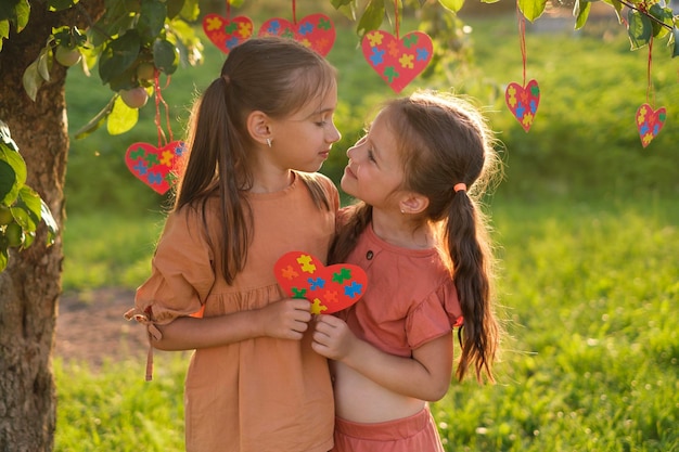 Los niños al atardecer mantienen juntos el corazón con piezas de rompecabezas mirándose unos a otros