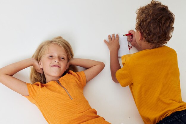 Foto niños alegres dibujando en cuadernos tirados en el suelo estilo de vida infantil inalterado