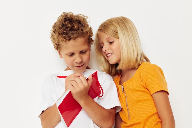 Los niños alegres se divierten en camisetas coloridas con un fondo de color de bloc de notas inalterado