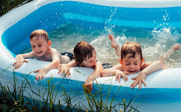 Los niños alegres y felices se acuestan en la piscina y salpican con sus pies los amigos pasan el ocio de verano