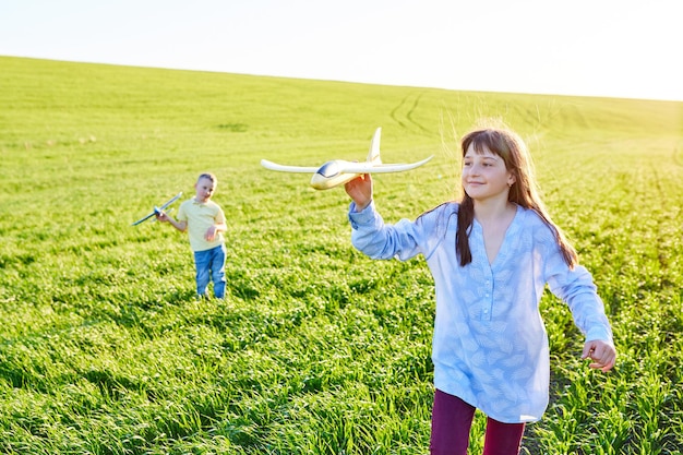 Los niños alegres y felices juegan en el campo y se imaginan a sí mismos como pilotos en un día soleado de verano Los niños sueñan con volar y la aviación