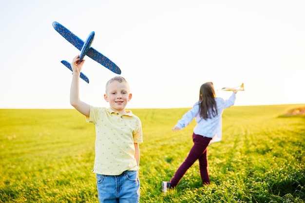 Los niños alegres y felices juegan en el campo y se imaginan a sí mismos como pilotos en un día soleado de verano Los niños sueñan con volar y la aviación