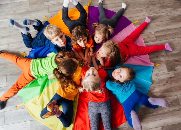 Niños alegres jugando juegos de formación de equipos en un piso