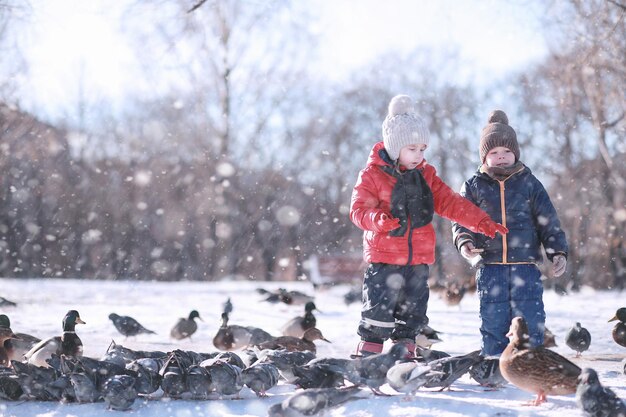 Los niños alimentan a los pájaros en el parque en invierno.