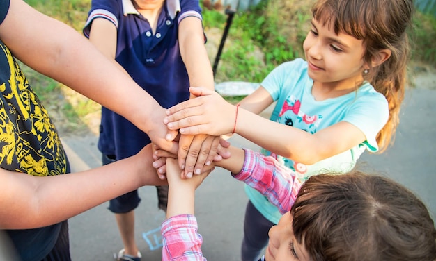 Los niños amigos juntan sus manos. Enfoque selectivo. Naturaleza.