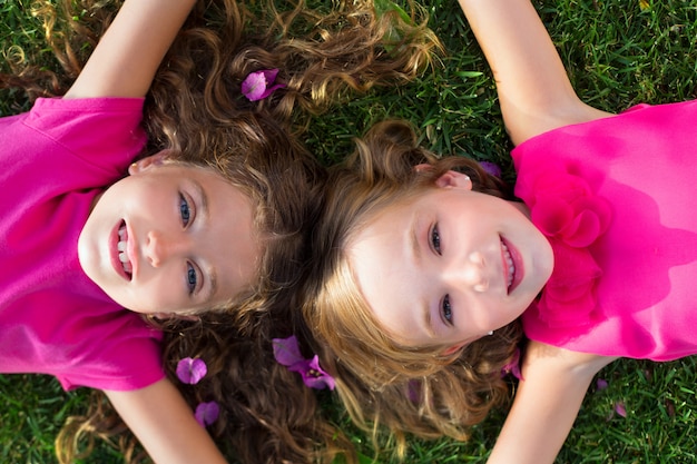 niños amigos niñas acostado en el jardín hierba sonriendo