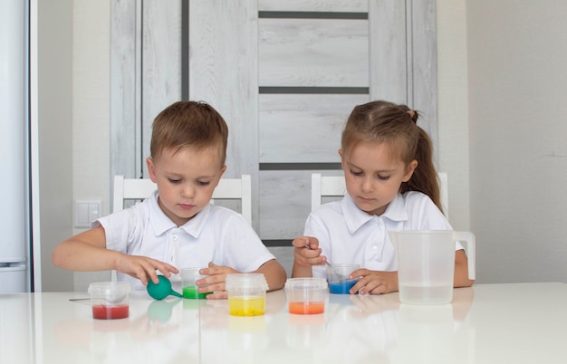 Foto los niños aprenden a mezclar diferentes colores con agua y pintura. desarrollo temprano. experimentos u observaciones químicas y científicas. . el concepto de ciencia de la educación. enfoque selectivo.