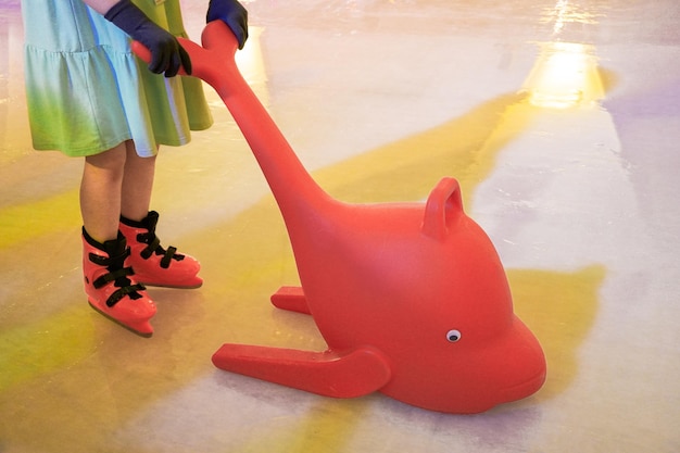 Foto los niños aprenden a patinar con formas de delfín rojo de plástico como ayudas de entrenamiento