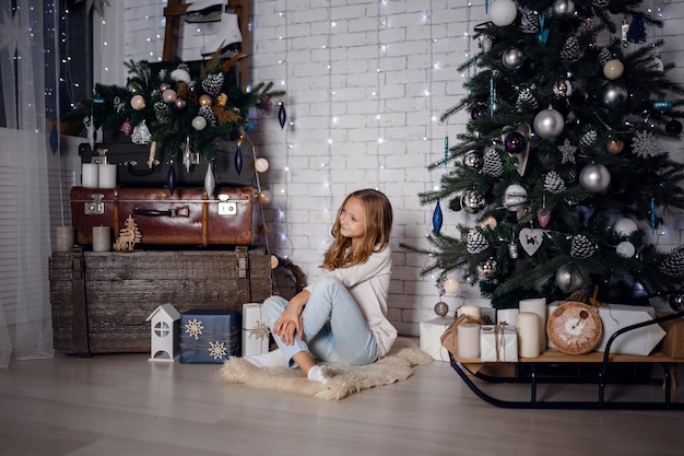 Niños bajo el árbol de Navidad con cajas de regalo. Decoraciones de año nuevo. estilo rústico, decoraciones de madera oscura. Interior de año nuevo. Hermanas.