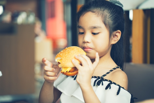 Los niños asiáticos comen pollo queso Hamburguesa Food Court