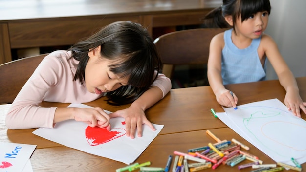 Niños asiáticos Dibujar y pintar en la mesa en la sala de juegos en casa Juego educativo