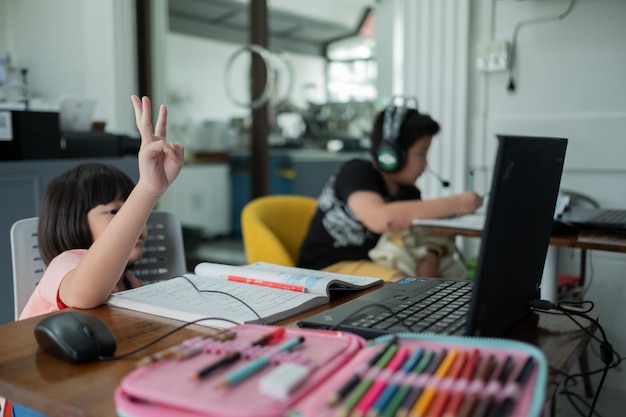 Los niños asiáticos están aprendiendo computadora en línea, escuela en casa