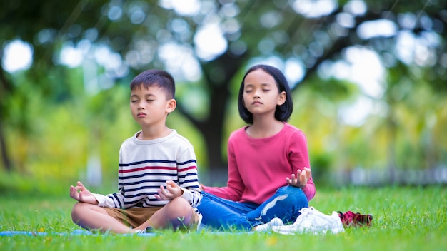 niños asiáticos haciendo yoga plantean en el parque al aire libre