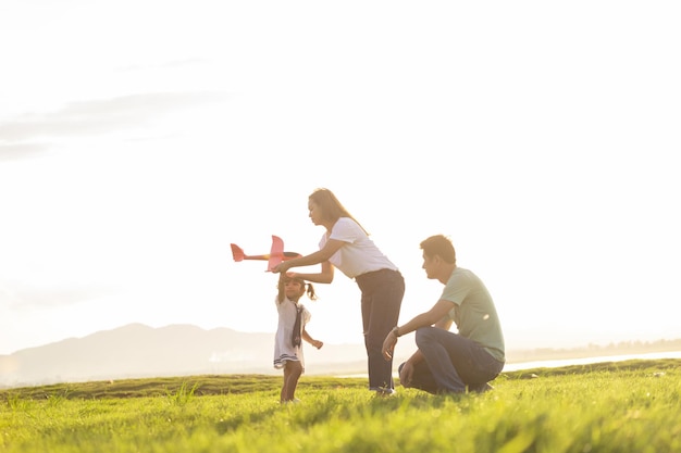 Foto niños asiáticos jugando al avión de cartón juntos en el parque al aire libre