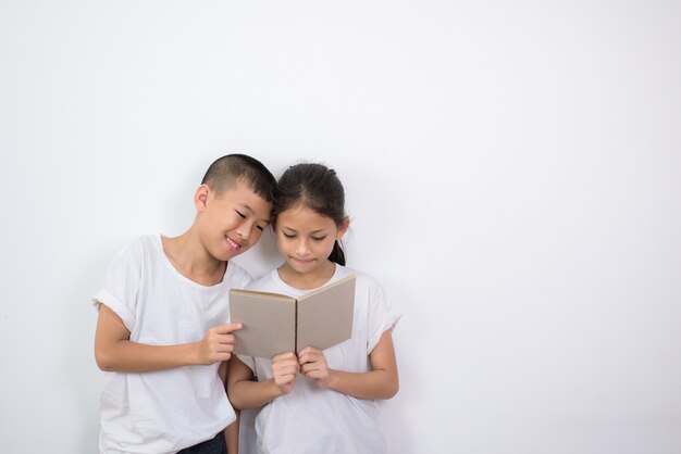 Niños asiáticos leyendo un libro juntos