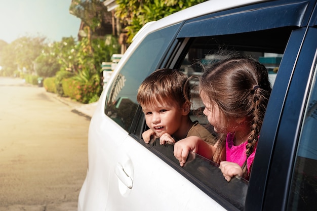 Los niños se asoman por la ventanilla del coche y miran la calle.