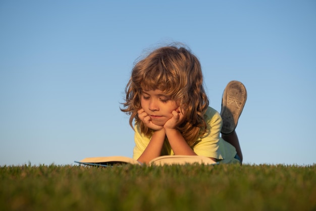 Los niños aventuran la libertad y los niños despreocupados lindo niño leyendo un libro al aire libre en el césped