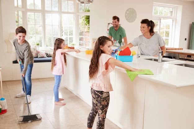 Niños ayudando a los padres con las tareas del hogar en la cocina