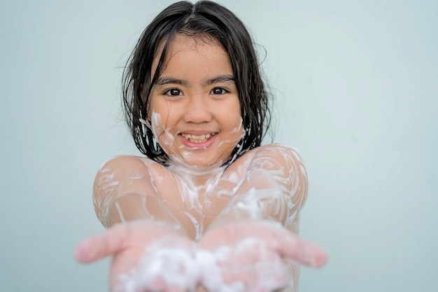 Los niños se bañan para limpiar el cuerpo una burbuja blanca al lado de su cuerpo cara bonita niño asiático sonriendo brillantemente