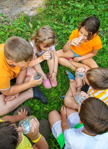 Los niños beben agua juntos al aire libre.