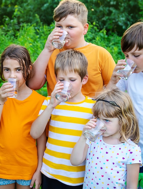 Los niños beben agua juntos al aire libre.