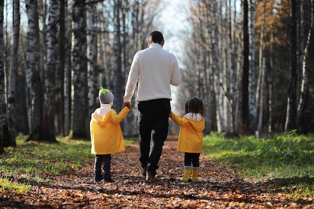 Los niños caminan en el parque de otoño en otoñoxA