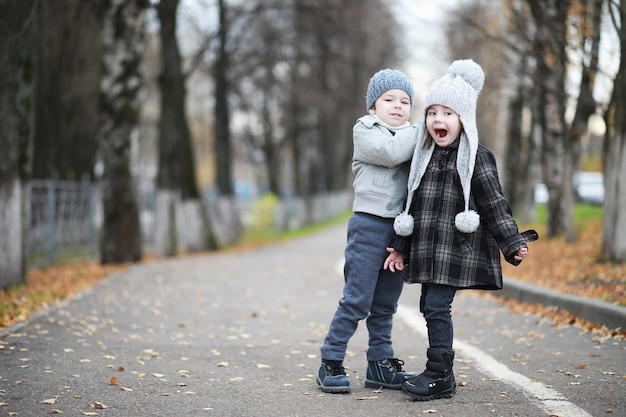 Los niños caminan en el parque de otoño en otoñoxA