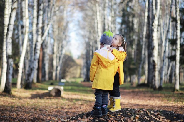 Los niños caminan en el parque de otoño en otoñoxA